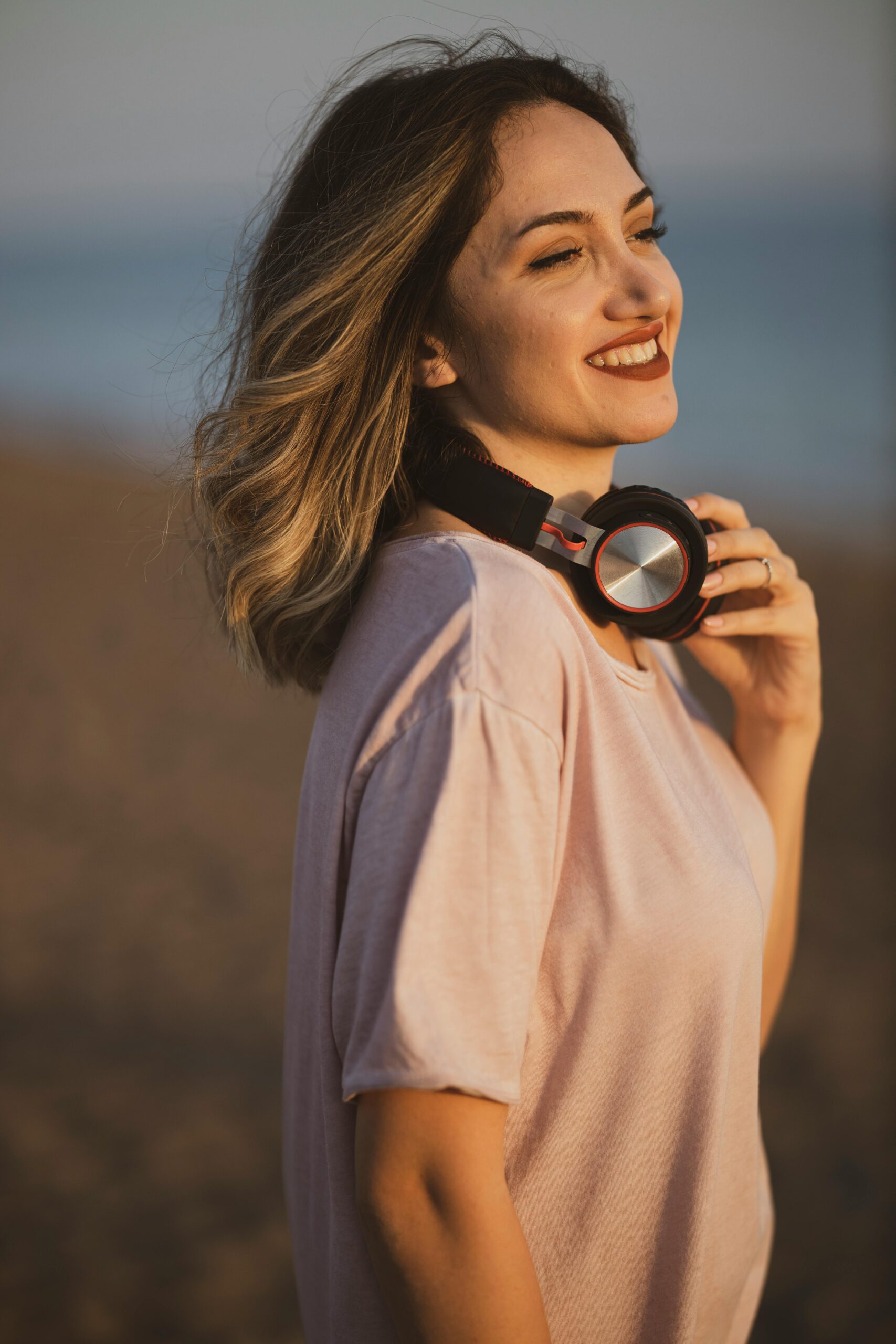 Smiling woman with headphones enjoying a sunny day on the beach.